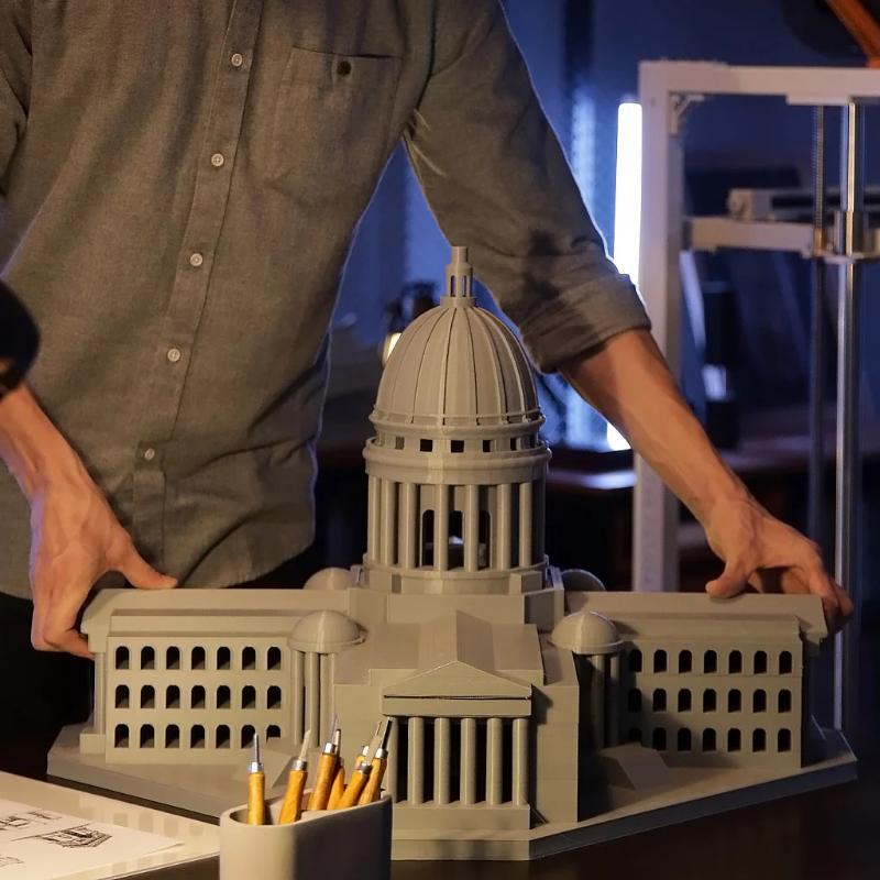 man holding stone grey building model created by elegoo orangestorm giga 3d printer