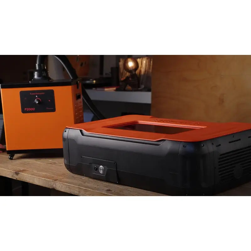 emblaser pro 60 watt laser cutter from front right side view with fume extractor to the left on a wooden table