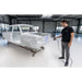 free scan trio laser 3d scanner in hand held use by a person on the right scanning a white car frame on the left