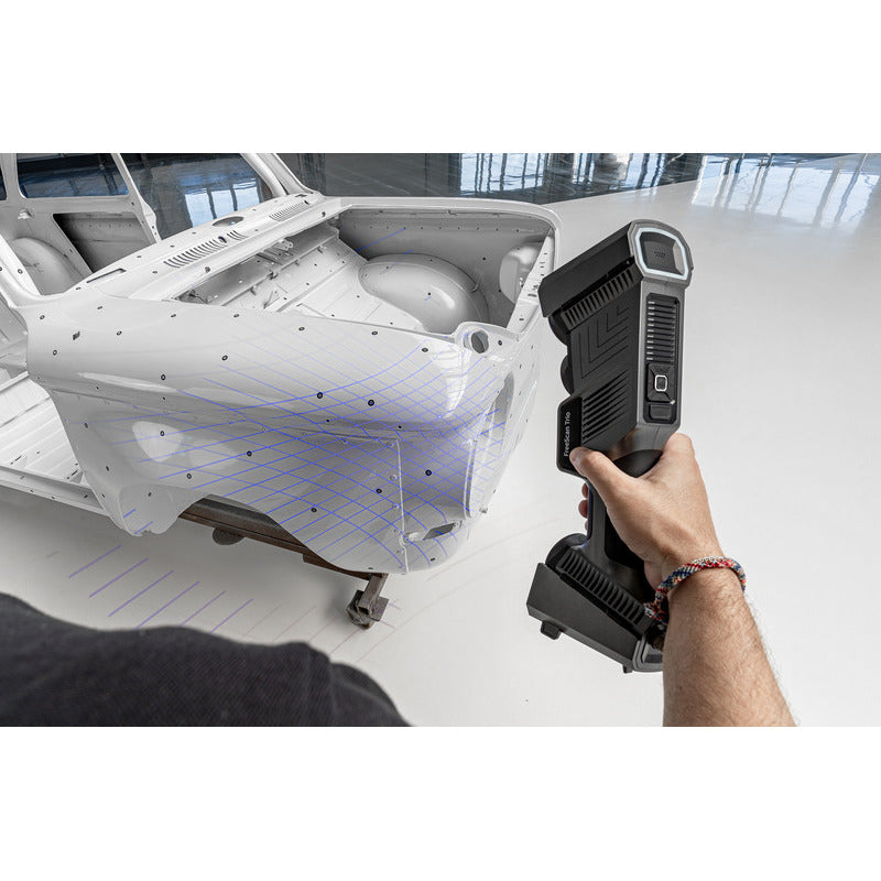 free scan trio laser 3d scanner in hand held use from a rear left angle scanning a white car frame on the left