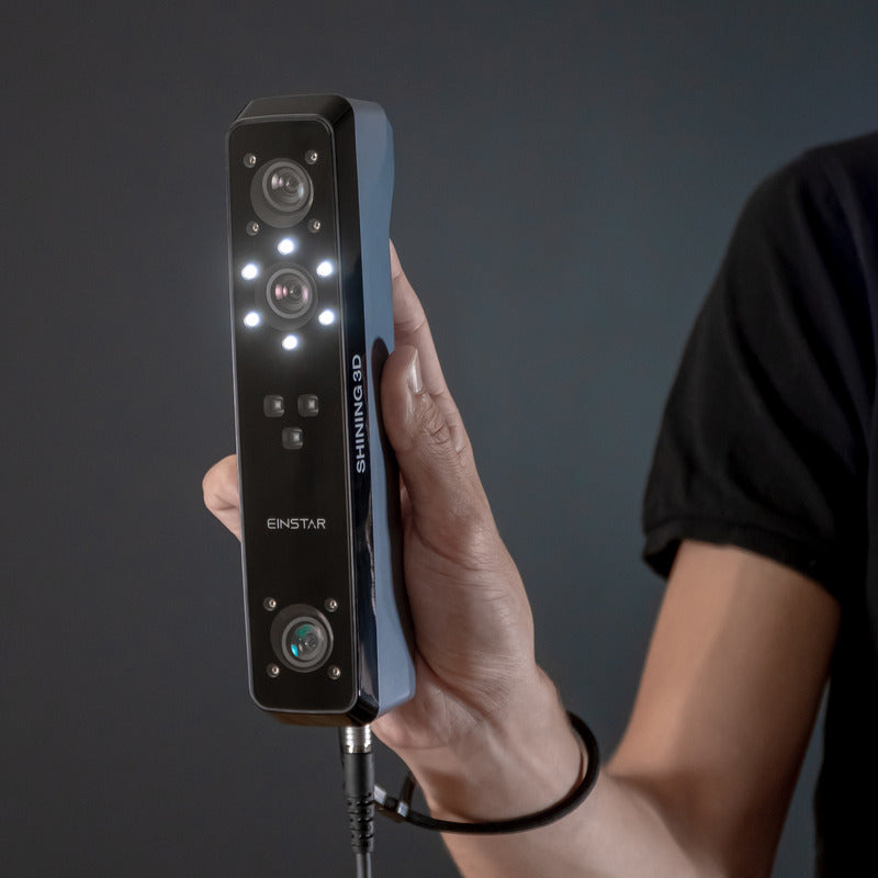 man holding shining 3d einstar scanner from front right side view with lights turned on in dark grey blue backdrop