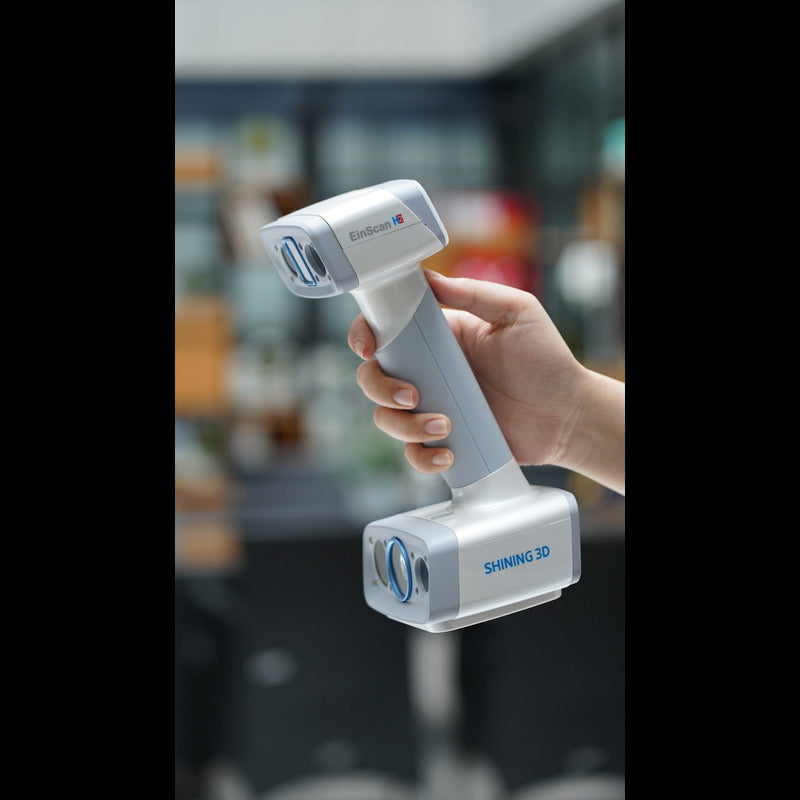hand holding a shining 3d einscan h2 scanner  with a blurred background