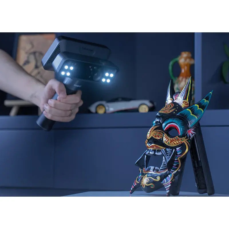 man in upper left corner scans dark coloured mask using shining 3d einscan rigil with lights on
