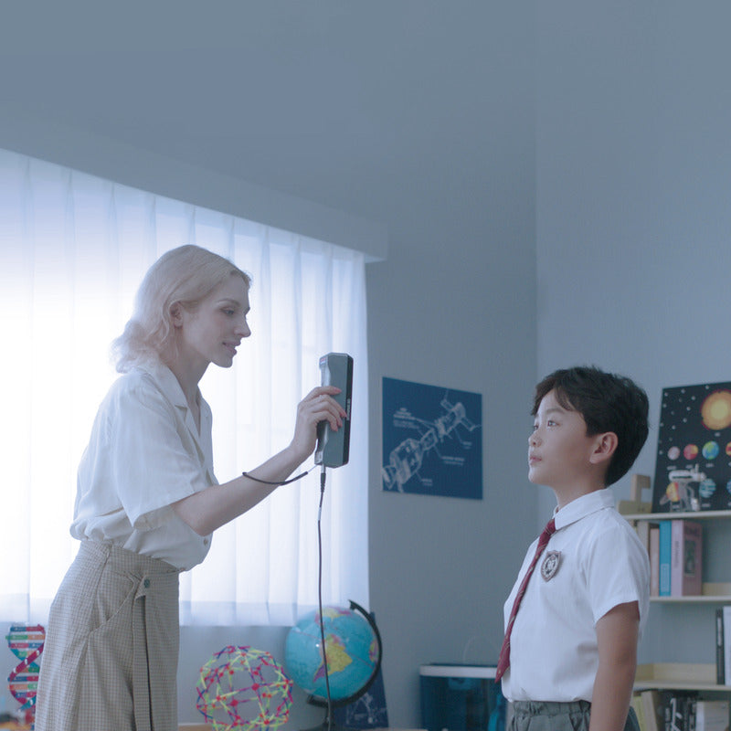 female teacher scans a young male student with a shining 3d einstar scanner in a classroom