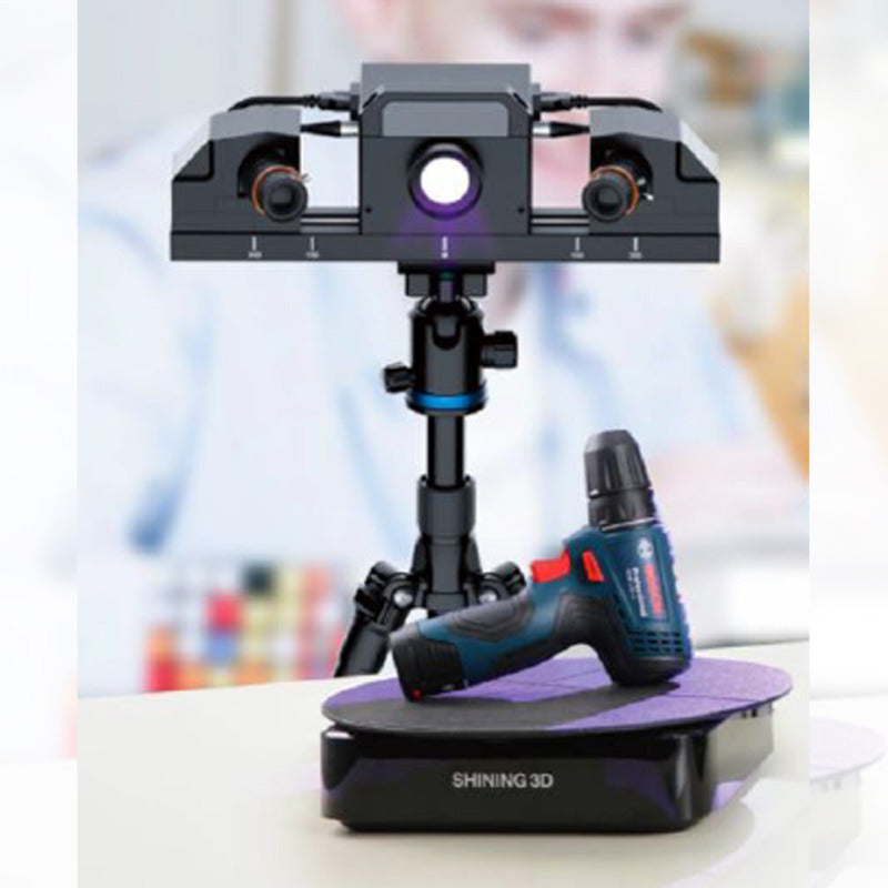 shining 3d transcan c mounted on a tripod scanning cordless drill on turntable with blurry background of a man